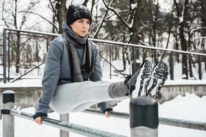 sportliche Frau während ihres Wintertrainings im Freien auf Barren foto