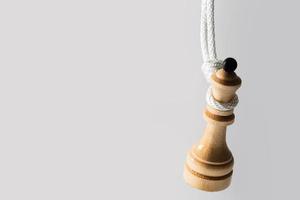 hölzerne Schachkönigin hängt an einem weißen Seil. foto