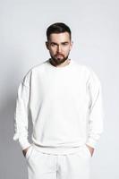 Schöner Mann mit weißem Sweatshirt und kabellosen Ohrstöpseln foto