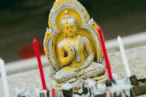 Nahaufnahme des buddhistischen Altars, der Kerzen und der betenden Buddha-Statue. foto