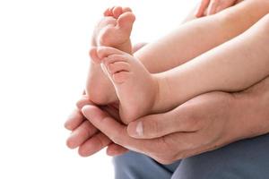 Die Hände des Vaters halten die Füße seines Babys foto