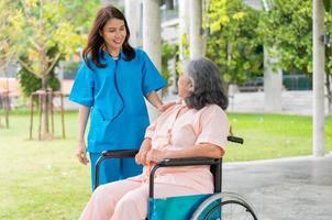 asiatische vorsichtige pflegekraft oder krankenschwester halten die hand des patienten und ermutigen den patienten im rollstuhl. Konzept des glücklichen Ruhestands mit Betreuung durch eine Pflegekraft und Spar- und Seniorenkrankenversicherung.