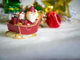 glücklicher weihnachtsmann mit geschenkbox auf dem schneeschlitten der hintergrund ist weihnachtsdekor. weihnachtsmann und weihnachtsdekor auf dem schnee. Konzept der frohen Weihnachten und des guten Rutsch ins neue Jahr foto