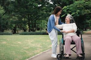 asiatische Pflegekraft oder Krankenschwester, die sich um den Patienten im Rollstuhl kümmert. Konzept des glücklichen Ruhestands mit Betreuung durch eine Pflegekraft und Spar- und Seniorenkrankenversicherung, eine glückliche Familie foto