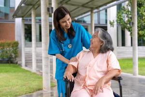 asiatische Pflegekraft oder Krankenschwester, die sich um den Patienten im Rollstuhl kümmert. Konzept des glücklichen Ruhestands mit Betreuung durch eine Pflegekraft und Spar- und Seniorenkrankenversicherung, eine glückliche Familie foto