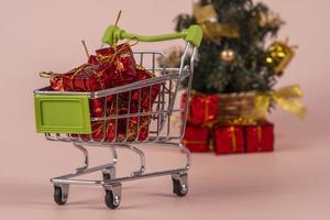 Weihnachtseinkaufswagen mit Geschenken und Weihnachtsbaum im Hintergrund foto