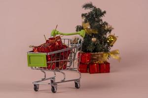 Weihnachtseinkaufswagen mit Geschenken und Weihnachtsbaum im Hintergrund foto