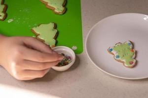 Mädchen verziert Lebkuchen mit Zuckerguss. Konzept der frohen Weihnachten und des guten Rutsch ins neue Jahr foto