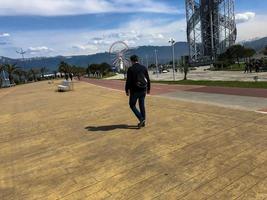 Ein Mann geht entlang der Promenade auf der Straße in einem tropischen, warmen Paradiesresort auf dem Hintergrund grüner Palmen und Berge foto