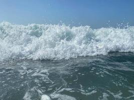 Wunderschönes Meer mit Wellen, die warmes, funkelndes, klares blaues Wasser in einem warmen, tropischen, orientalischen Land im Süden spritzen. Hintergrund, Textur foto