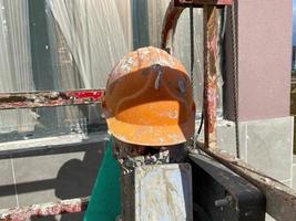 Gelber Kunststoffschutz schmutzig zerkratzter alter Bauarbeiterhelm, um den Kopf vor herabfallenden Gegenständen auf der Baustelle zu schützen foto
