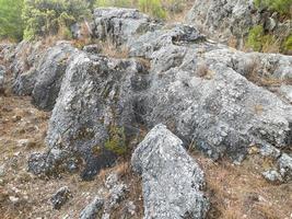 ein großer stein, ein kopfsteinpflaster ragt aus dem boden und daneben wird grüner naturrasen gemahlen. Berglandschaft foto