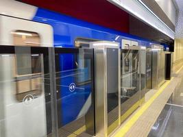 Ein blauer Waggon mit offener und geschlossener mechanischer Schiebetür und Mann an einem U-Bahn-Bahnsteig foto