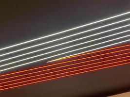 textur von rot-weiß leuchtenden hellen neon-led-mehrfarbigen laser-abstrakten streifen und linien von parallelen lampen. der Hintergrund foto