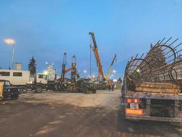 Bau einer kaputten Brücke an einer stark befahrenen Straße. Baumaschinen auf der Baustelle errichten eine Überführung. LKW trägt einen Metallrahmen foto