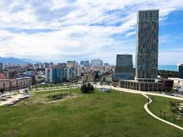 grüner park in einer modernen großstadt, megalopolis mit hohen glashäusern, gebäuden, wolkenkratzern gegen den blauen himmel der berge an einem tropisch warmen sommerfrischeort, ruhe foto