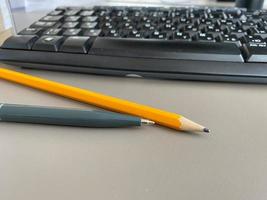 Automatischer grüner Kugelschreiber und Schreibbleistift auf dem Schreibtisch mit Computertastatur. geschäftliche Arbeit foto
