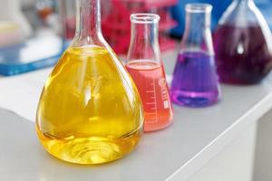 chemischer laborkolben mit blau-lila-rosa flüssigkeitsständer auf dem tisch foto