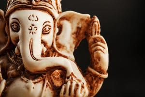 Hindu-Gott Ganesh auf schwarzem Hintergrund. Statue mit Räucherstäbchen foto