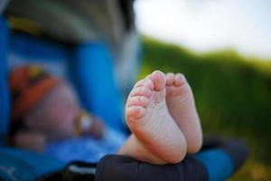 süße, lustige, sanfte Absätze eines Kindes vor dem Hintergrund eines Liegens in einem Kinderwagen foto