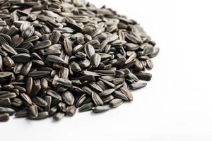 Samen in einer schwarzen Schale sind ein Haufen auf weißem Hintergrund. im Vollbildmodus foto