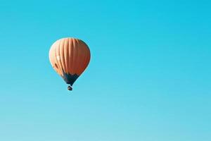 Orangefarbener Ballon schwebt gegen den blauen Himmel foto