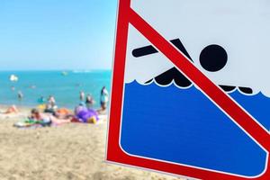 ein schild am strand darf trotz schild und verbot nicht schwimmen menschen baden und sich im meer ausruhen. foto