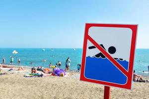 ein schild am strand darf trotz schild und verbot nicht schwimmen menschen baden und sich im meer ausruhen. foto