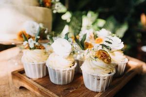 Gourmet-Cupcakes mit weißem Buttercreme-Zuckerguss und Streuseln auf Holzhintergrund foto