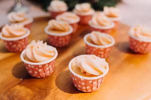 Gourmet-Cupcakes mit weißem Buttercreme-Zuckerguss und Streuseln auf Holzhintergrund foto