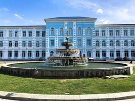 das blaue schöne gebäude der staatlichen universität batumi und der brunnen davor. Batumi, Georgien, 17. April 2019 foto