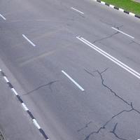 beschädigte schlechte asphaltstraße mit schlaglöchern. Patch-Reparatur von Asphalt foto