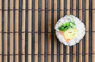 Sushi-Rolle liegen auf einer Nähmatte aus Bambusstroh. traditionelles asiatisches essen. Ansicht von oben. flacher Laienminimalismus mit Kopierraum foto