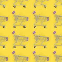 Einkaufssucht, Einkaufsliebhaber oder Shopaholic-Konzept. Viele kleine leere Einkaufswagen führen ein Muster auf einem pastellfarbenen Papierhintergrund durch. flache Laienzusammensetzung, Draufsicht foto