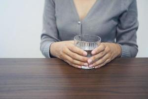 weibliche hand, die ein glas wasser hält, wählen sie nahfokuskonzept der gesunden, schönheitshautpflege aus. foto