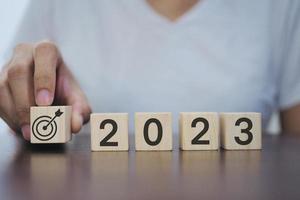 2023 Neujahrsziele, Pläne, Ideen, Inspirationskonzept. Geschäftsmann hält einen Holzklotz mit Zielsymbol 2023, Konzept 2023. foto