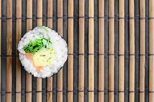 Sushi-Rolle liegen auf einer Nähmatte aus Bambusstroh. traditionelles asiatisches essen. Ansicht von oben. flacher Laienminimalismus mit Kopierraum foto