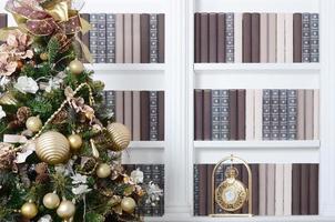 ein wunderschön geschmückter weihnachtsbaum auf dem hintergrund eines bücherregals mit vielen büchern in verschiedenen farben und einer goldenen uhr. Weihnachten Hintergrundbild der Bibliothek foto