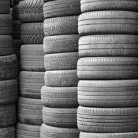 Alte gebrauchte Reifen, die mit hohen Stapeln in der Garage des sekundären Autoteilegeschäfts gestapelt sind foto