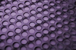 Computergehäuse aus schwarzem Metall mit Löchern auf violettem Hintergrund. abstrakt hautnah
