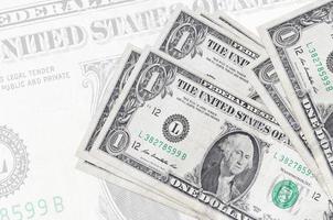 1 us-dollarscheine liegen im stapel auf dem hintergrund einer großen halbtransparenten banknote. abstrakte Darstellung der Landeswährung foto