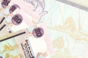 20 srilankische Rupien-Scheine liegen im Stapel auf dem Hintergrund einer großen halbtransparenten Banknote. abstrakter betriebswirtschaftlicher hintergrund foto