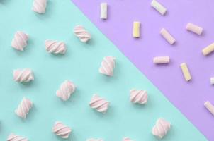 bunter Marshmallow auf violettem und blauem Papierhintergrund. pastellfarbenes, kreatives Strukturmuster. minimal foto