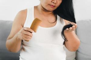 Problem mit Haarausfall. asiatische frau mit kamm- und haarproblem. Haarausfall durch Kamm. Haarpflege- und Schönheitskonzepte. foto