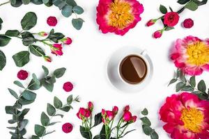 Tasse Kaffee am Morgen und schöne Rosen und Pfingstrosen auf weißem Hintergrund, Draufsicht. foto