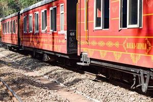 Spielzeugeisenbahn, die sich auf Berghängen bewegt, schöne Aussicht, ein Seitenberg, ein Seitental, das sich auf der Eisenbahn zum Hügel bewegt, inmitten grüner Naturwälder. spielzeugeisenbahn von kalka nach shimla in indien, indischer zug foto