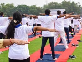 Gruppen-Yoga-Übungssitzung für Menschen verschiedener Altersgruppen im Cricket-Stadion in Delhi am internationalen Yoga-Tag, große Gruppe von Erwachsenen, die an Yoga-Sitzungen teilnehmen foto