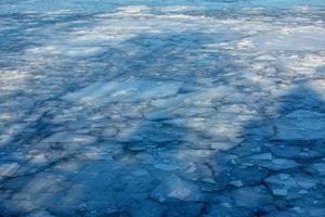 Winternaturhintergrund mit Eisblöcken auf gefrorenem Wasser im Frühjahr. abstrakter hintergrund von treibendem eis auf dem wasser. foto