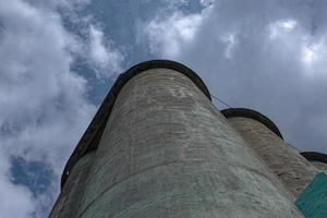 Kornelevator gegen einen stürmischen Himmel. Große Fabrikstruktur vor blauem Himmel, niedrige Winkelansicht. foto