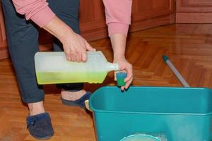 Wischen Sie Ihren Holzboden. Eine Frau bereitet eine spezielle Lösung zum Waschen von Parkett vor. Housekeeping-Konzept. foto